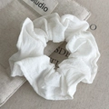 Detailed close-up of white textured fabric scrunchie on a beige storage bag background - White