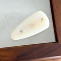 Detalle macro de la pinza de pelo de acetato vintage con textura iridiscente y pedrería fina - Blanco Leche con Strass Blanco