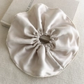 Dettaglio macro dello scrunchie in raso champagne con trama setosa su un libro - Stile Albicocca (26448A)