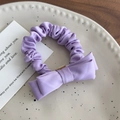 Dettaglio di un elastico per capelli con fiocco lavanda su un piatto di ceramica a pois - Viola