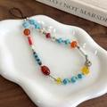 Detailed close-up of colorful beaded phone strap with blue, red and yellow beads on tray - Red and Blue Beaded Style