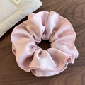 Detail of light pink pleated satin scrunchie showing stitching and soft silk texture - Pink