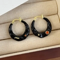 Detail macro view of retro black and gold C-shaped earrings with red gem accents - Black