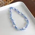 Gros plan d'une dragonne de téléphone en perles colorées avec un pendentif papillon - Bleu Iridescent