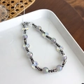 Détail de la dragonne de téléphone en perles irisées avec papillons sur une assiette blanche - Noir Irisé