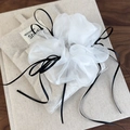 Detailopname van witte organza scrunchie met lang zwart lint op een textuur ondergrond - Zwart lint