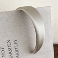 Detalle de una diadema acolchada de satén champán con diseño de copa alta sobre un libro - Albaricoque