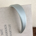 Primer plano de una diadema ancha de satén azul grisáceo sobre un libro decorativo - Azul