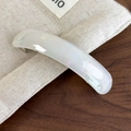 Detailed view of curved acetate hair clip with milky white pearlescent finish on fabric - Jade White