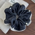 Detalle de un coletero de satén negro con bordes de encaje blanco y perlas decorativas - Negro
