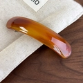 Close-up of tortoise shell pattern hair clip on elegant cream fabric and wood surface - Brown Coffee