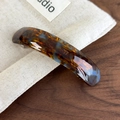 Detail of a curved tortoiseshell hair clip with a glossy finish and a cotton storage bag - Mocha Blue