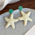 Detailed macro view of woven raffia starfish earrings in beige and emerald green - Starfish Woven Drop Earring (26554A)