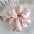 Macro detail of oversized organza scrunchie with a shimmering pearlescent satin texture - Pink