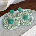 Detailed macro view of green raffia woven sunflower earrings on a stone jewelry tray - Sunflower 3D Radial Style (26554B)