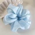 Detail of light blue organza hair scrunchie with glossy texture and elegant pleats - Blue