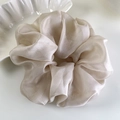 Detail of oversized champagne organza scrunchie with a silk-like texture and soft pleats - Champagne