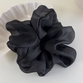 Detail of a large black organza scrunchie with a silky texture next to a ceramic bowl - Black
