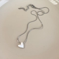 Gros plan sur la chaîne serpent argentée avec pendentif cœur sur plateau en céramique - Style Cœur (26565A)