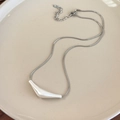 Détail de la chaîne serpent argentée avec pendentif blanc sur plateau céramique - Style Tube Incurvé (26565C)