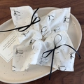 Detail of white lace scrunchie with black ribbon bow and floral patterns on ceramic tray - White