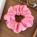 Primer plano de coletero rosa fruncido en tela suave sobre una bandeja de madera - Rosa