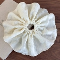 Detalle de un elegante coletero crema en tela de jacquard texturizada sobre un libro - Blanco Roto