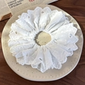 Dettaglio di scrunchie in pizzo bianco ricamato con motivi a cuore su piatto di ceramica - Bianco