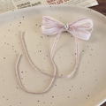 Detalle de horquilla con lazo de malla rosa y cristal brillante sobre plato cerámico - Rosa