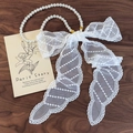 French retro pearl necklace with a large white lace mesh bow on a dark wood background - Striped Lace Style (26609A)