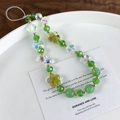 Detail of beaded phone strap with green glass beads, aurora butterfly, and flower charms - Iridescent Green