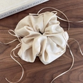 Detail of champagne organza ribbon bow scrunchie with soft pleats on a wooden background - Coffee