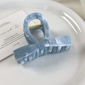 Detailed macro view of light blue marble acetate hair claw with golden spring mechanism - Metallic Blue