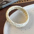 Detail of hand-woven rattan bangle with intricate beige texture on a ceramic plate - Creamy White Arc Woven (26684C)
