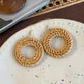 Detail van ronde gevlochten rotan oorbellen op een wit keramisch dienblad in boho stijl - Koffie