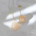 Close-up of pink glitter cherry resin earrings with golden hooks on white background - Apricot Yellow