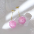 Macro view of pink cherry resin earrings with fine gold glitter on wavy white base - Lavender