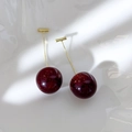 Detail view of cherry earrings with deep red glitter resin spheres and gold-plated metal stems - Cherry Red