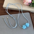 Détail d'un collier choker à fleurs bleu clair avec rubans en velours sur un plateau - Fleur Bleue Mate (26726E)