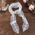 Detail of white floral lace scarf with embroidery and scalloped edges on a wooden table - Straight Vine (26737C)