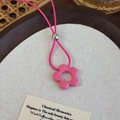 Detalle de un colgante de flor rosa en un cordón trenzado con una cuenta de plata metal - Flor Rosa Roja