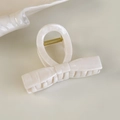 Vista lateral de una pinza para el cabello color crema con forma de lazo y textura mármol - Lazo Blanco (26676A)