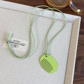 Detailed close-up of a light green comb-shaped acrylic pendant on a minimalist necklace - Green
