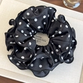 Close-up of black satin scrunchie with white polka dots and layered ruffle edges - Black With White Polka Dots