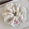 Detailansicht eines floralen Scrunchies mit Spitzenkante, rosa Schleife und Knopf - Rosa Blumenmuster Runde Ausführung