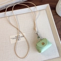 Détail de la mini pochette en cuir menthe avec bouton doré et cordon tressé ajustable - Sac Vert