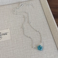 Detalle de collar de flores de plata con piedras azules en bandeja beige - Colgante de flor de cuentas redondas (26809A)