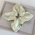 Close-up of yellow plaid fabric scrunchie with lace edge and green floral button detail - Yellow Square Style