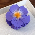 Detail shot of a matte purple floral hair claw clip with yellow gradient center on fabric - Purple Flower