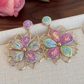 Dettaglio di orecchini a fiore in rafia intrecciata colorata con cornici dorate - Stile Fiore